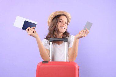 Güneş gözlüğü, kırmızı çanta, mor arka plan üzerinde izole pasaport ile plastik kredi kartı gösteren turist kız.