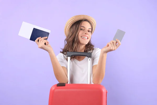 Fille touristique en montrant carte de crédit en plastique avec des lunettes de soleil, valise rouge, passeport isolé sur fond violet . — Photo