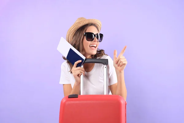 Jeune fille touristique en vêtements décontractés d'été, avec des lunettes de soleil, valise rouge, passeport isolé sur fond violet . — Photo