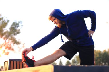 Açık havada duran süre çalıştırmadan önce germe yapan yakışıklı genç erkek egzersizleri.