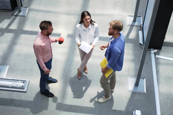 Vue du dessus des jeunes gens modernes en vêtements décontractés intelligents discutant affaires tout en se tenant dans le bureau créatif . — Photo