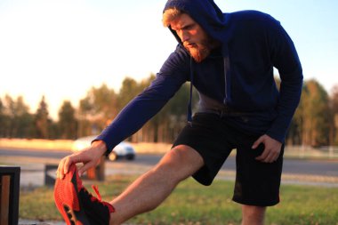 Açık havada duran süre çalıştırmadan önce germe yapan yakışıklı genç erkek egzersizleri.