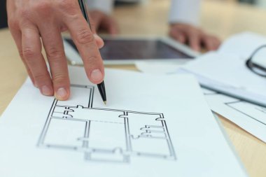 ev planları üzerinde elektronik tablet gösteren emlakçı.