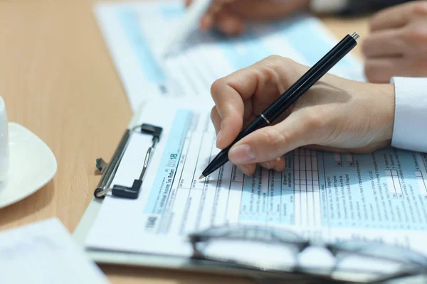 Woman filling in U.S. Individual income tax return, tax 1040 at table. — Stock Photo, Image
