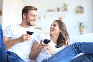 Genç bir çift oturma odasında bir bardak kırmızı şarap içiyor..