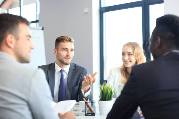 Empresários discutem algo enquanto se sentam juntos à mesa . — Fotografia de Stock