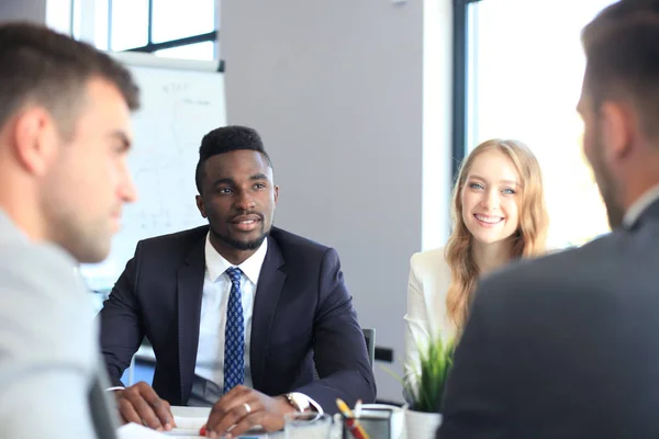 Empresários discutem algo enquanto se sentam juntos à mesa . — Fotografia de Stock