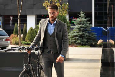 Kendine güvenen genç işadamı şehirde sokakta Bisiklet ile ayakta.