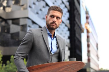 Sokakta yürürken kendine güvenen genç iş adamı Longboard kullanarak.