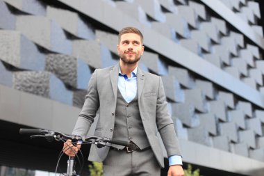 Kendine güvenen genç işadamı bisiklet ile şehirde sokakta yürüme.