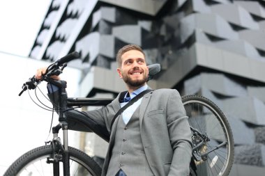 Kendine güvenen genç işadamı açık havada yürürken onun bisiklet taşıma.