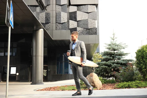 Zeker jonge zakenman lopen op de straat, met behulp van longboard. — Stockfoto