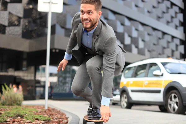 Zeker jonge zakenman in business man in pak longboard haast naar zijn kantoor, op de straat in de stad — Stockfoto