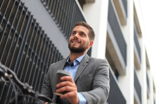 Zeker jonge zakenman met zijn fiets buiten koffie drinken. — Stockfoto