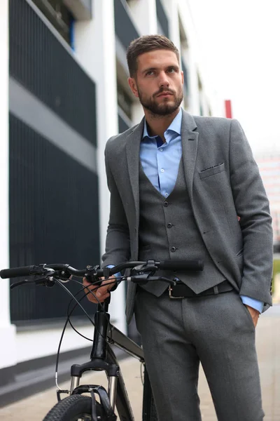 Joven empresario seguro paseando en bicicleta por la calle de la ciudad . — Foto de Stock