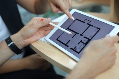 ev planları üzerinde elektronik tablet gösteren emlakçı.