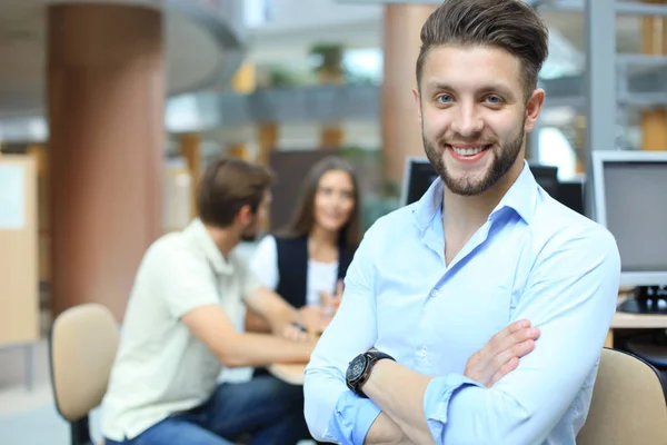 Joven sosteniendo tableta digital mientras sus colegas trabajan en segundo plano . — Foto de Stock