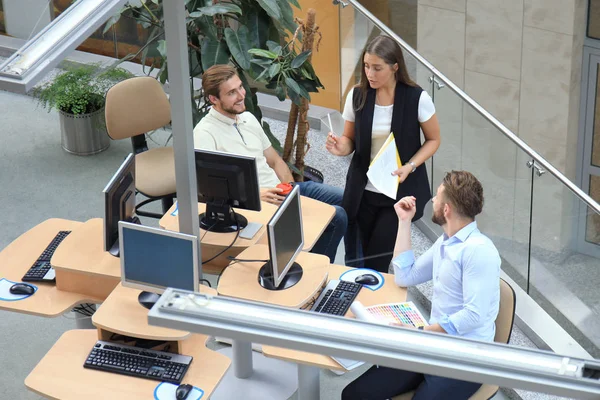 Visão superior de jovens colegas modernos em desgaste casual inteligente trabalhando juntos enquanto passam tempo no escritório . — Fotografia de Stock