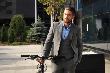 Kendine güvenen genç işadamı şehirde sokakta Bisiklet ile ayakta.