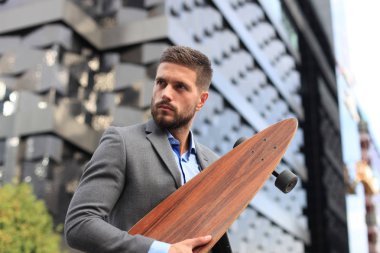 Sokakta yürürken kendine güvenen genç iş adamı Longboard kullanarak.