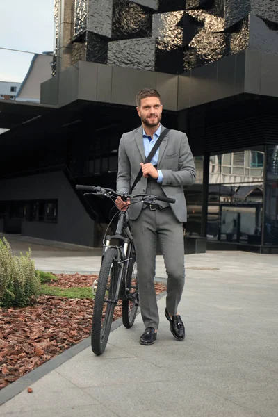 Joven empresario seguro paseando en bicicleta por la calle de la ciudad . — Foto de Stock
