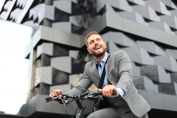 Beau jeune homme d'affaires à vélo en plein air dans la ville . — Photo