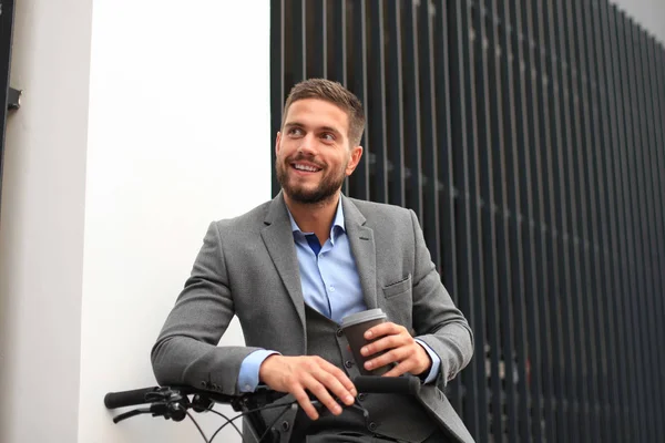 Joven empresario confiado con su bicicleta bebiendo café al aire libre . — Foto de Stock