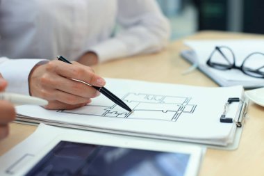 ev planları üzerinde elektronik tablet gösteren emlakçı.