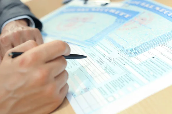 Close-up van persoon hand met pen vullen lege sociale zekerheid. — Stockfoto