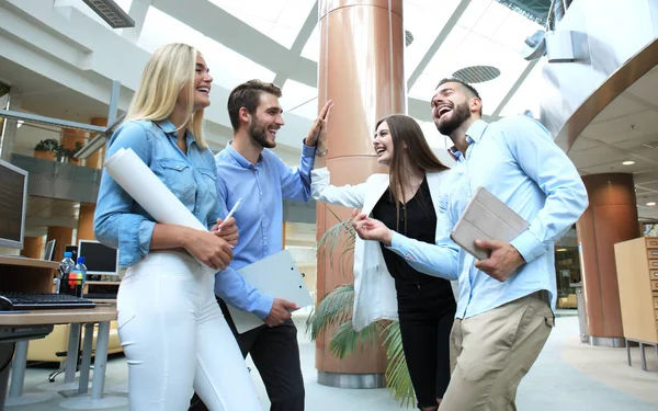 Jóvenes felices de pie en el cargo y dando choca a sus colegas . — Foto de Stock