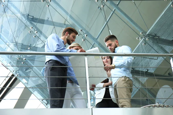 Vista de abajo. Gente moderna en ropa casual teniendo una reunión de tormenta de ideas mientras está de pie en la oficina creativa . —  Fotos de Stock