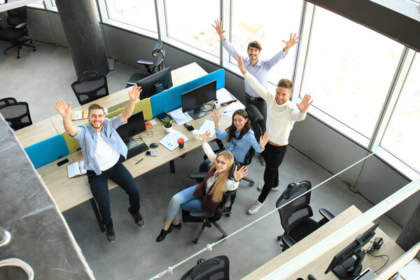 Top view of young modern colleagues in smart casual wear working together while spending time in the office.