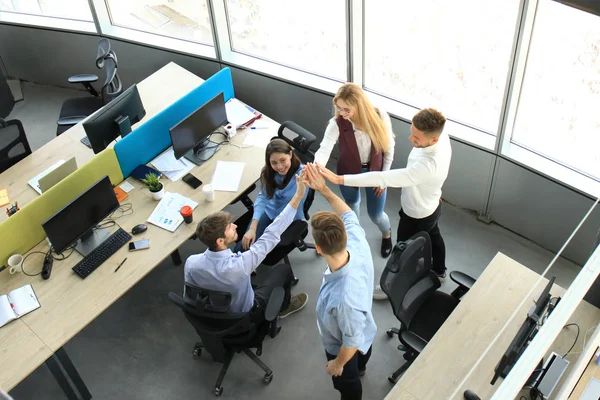 Vista dall'alto dei giovani colleghi moderni in abbigliamento casual intelligente che lavorano insieme mentre trascorrono del tempo in ufficio . — Foto Stock