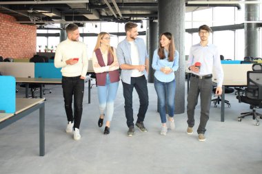 Gençlerin iş tartışmak ve ofis aracılığıyla yürürken gülümseyen akıllı rahat kıyafet içinde tam uzunlukta.