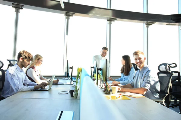 Jóvenes colegas modernos en ropa casual inteligente trabajando juntos mientras pasan tiempo en la oficina creativa . —  Fotos de Stock