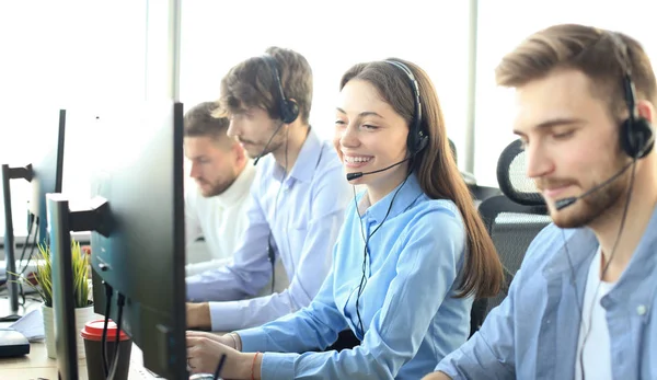 Portret van callcenter medewerker vergezeld door haar team. Lachende klant support operator aan het werk. — Stockfoto
