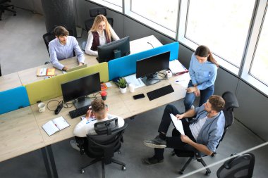 Top view of young modern colleagues in smart casual wear working together while spending time in the office. clipart