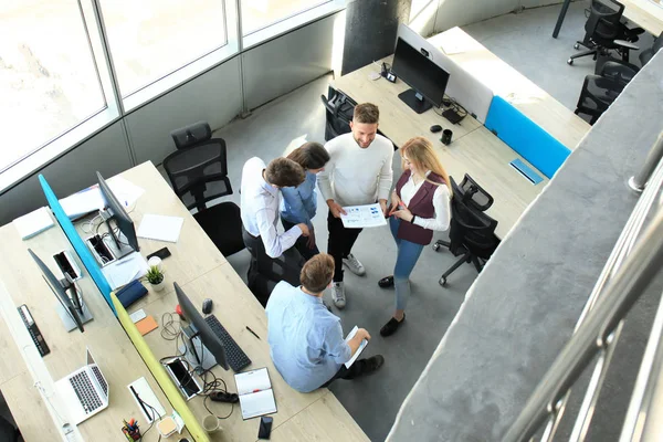 Vista superior de los jóvenes colegas modernos en ropa casual inteligente trabajando juntos mientras pasan tiempo en la oficina . — Foto de Stock