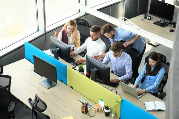 Vista dall'alto dei giovani colleghi moderni in abbigliamento casual intelligente che lavorano insieme mentre trascorrono del tempo in ufficio . — Foto Stock