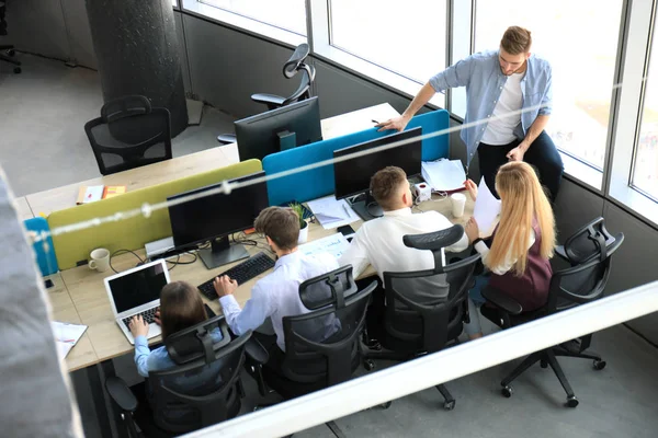 Ovanifrån av unga moderna kolleger i smart fritidskläder arbetar tillsammans medan spendera tid på kontoret. — Stockfoto