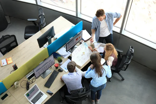 Vista superior de los jóvenes colegas modernos en ropa casual inteligente trabajando juntos mientras pasan tiempo en la oficina . —  Fotos de Stock