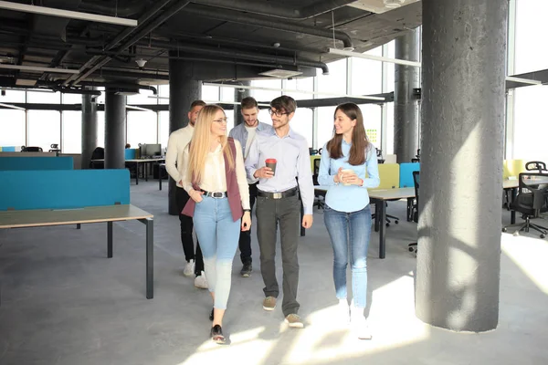 Полная длина молодых людей в элегантной повседневной одежде обсуждают бизнес и улыбаются во время прогулки по офису . — стоковое фото