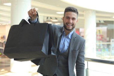 yakışıklı erkek takım elbise ile alışveriş torbaları.