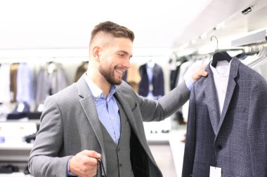 şık genç adam alışveriş merkezi veya giyim mağazasında yeni takım seçimi.