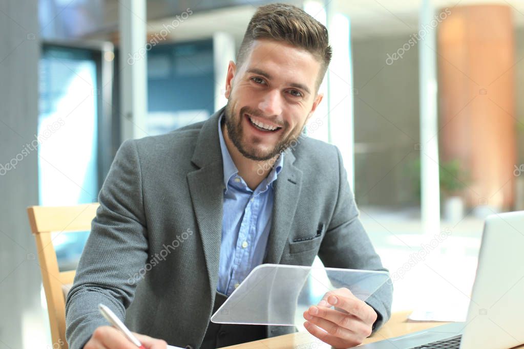 Businessman working in office with transparent tablet and laptop.