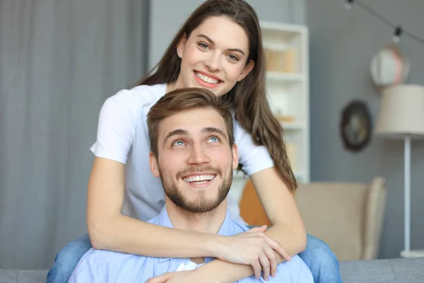 Krásná žena s přítelem tráví čas pohromadě na pohovce doma v obýváku.. — Stock fotografie