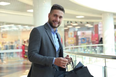 yakışıklı erkek takım elbise ile alışveriş torbaları.