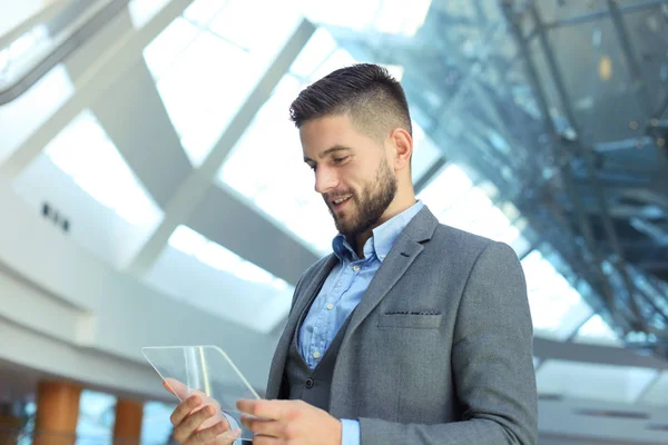 Businessman working in office with transparent tablet and laptop.