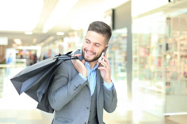 Jeune homme d'affaires avec sac à provisions parlant au téléphone à l'intérieur . — Photo