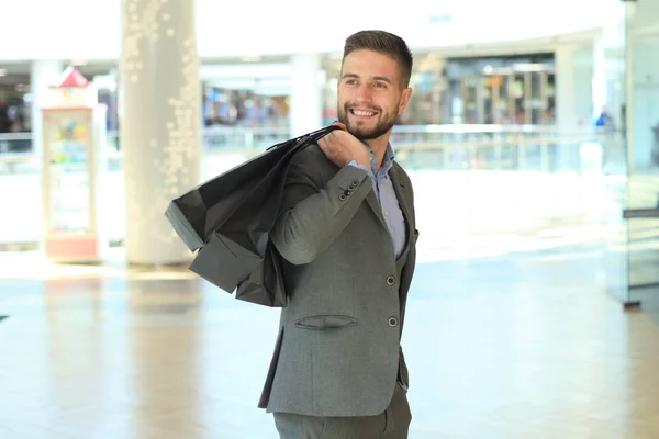 Hombre guapo en traje con bolsas de compras . — Foto de Stock